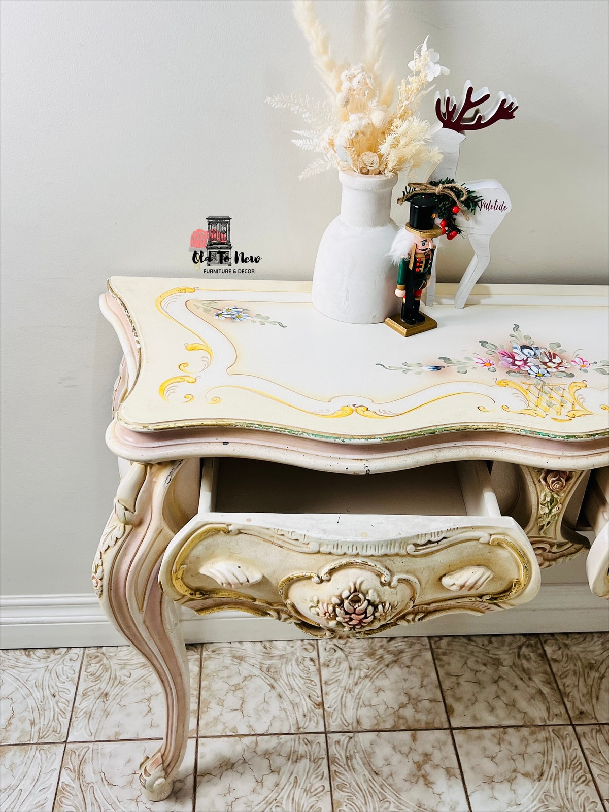 Decorative side table with floral patterns and gold accents on a tiled floor.