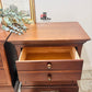 Wooden nightstand with an open drawer, framed picture, and plant in the background. Old to New Furniture & Decor, Canada