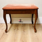 Unfinished wooden bench with pink cushion on a wooden floor against a white wall, available for customization 