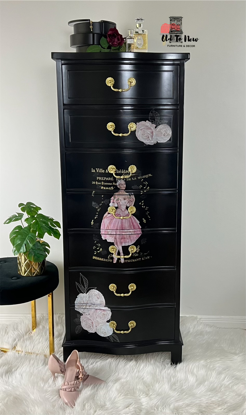 Black dresser with floral and decorative graphics on a white floor and light gray wall.