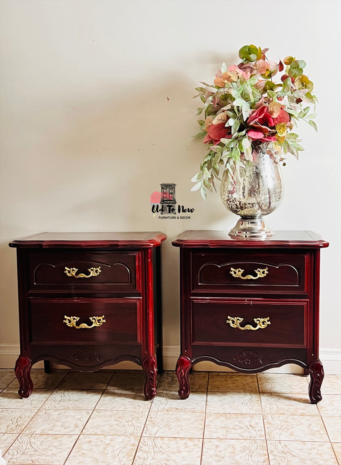 Two wooden French Provincial nightstands with floral arrangement on a tiled floor.