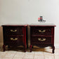 Pair of dark wood French Provincial nightstands with gold handles on a tiled floor.