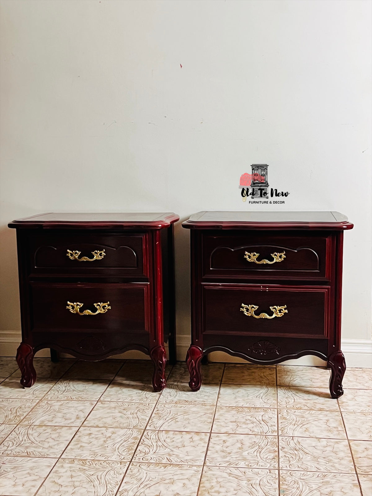 Pair of dark wood French Provincial nightstands with gold handles on a tiled floor.
