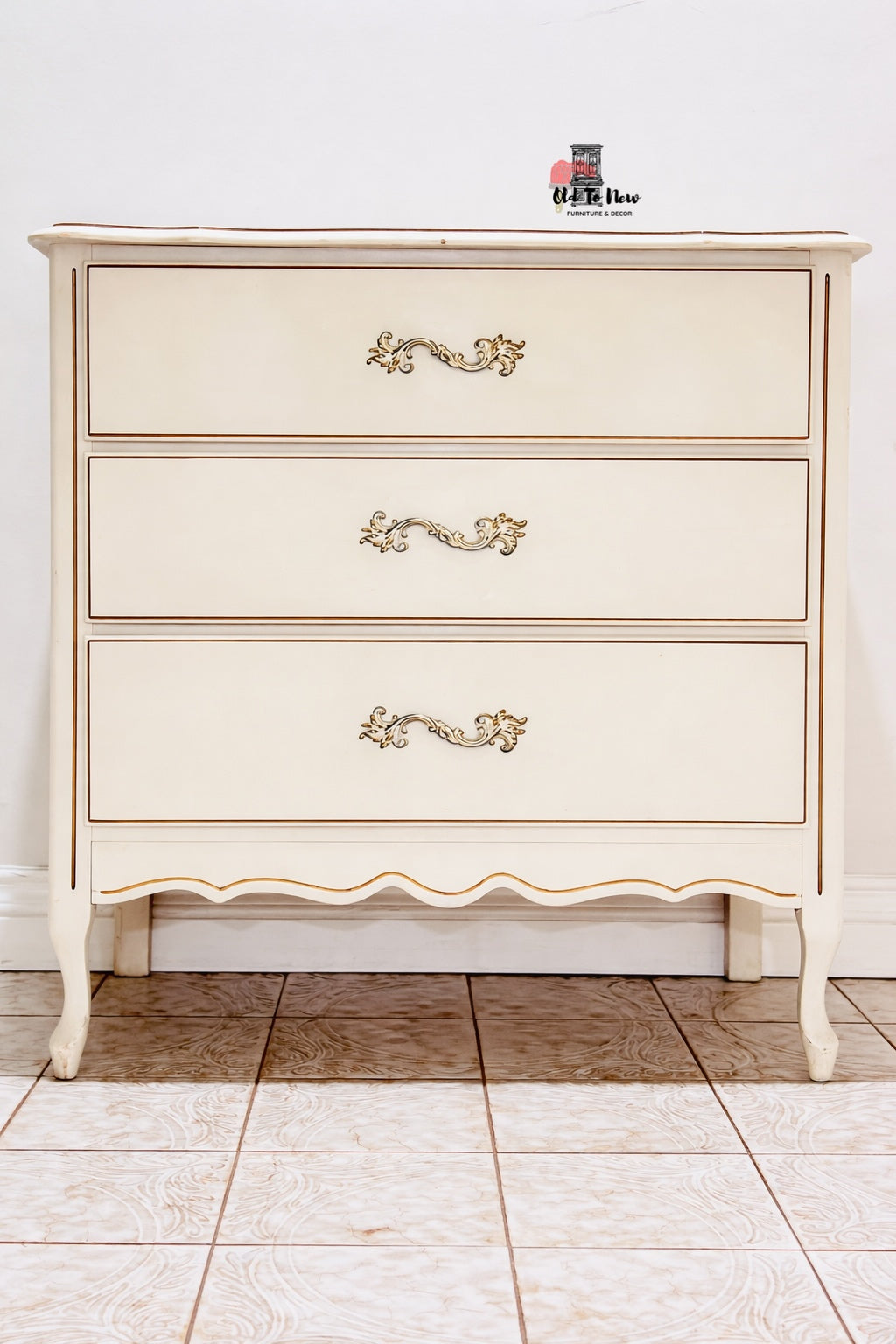 French Provincial dresser with decorative handles on a tiled floor.